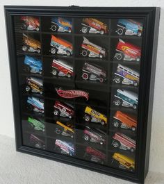 a display case filled with lots of different types of toy cars on top of a white wall