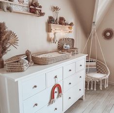 a white dresser topped with baskets next to a baby's crib in a room