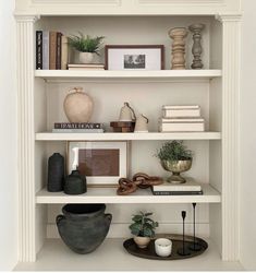 a white book shelf filled with books and vases