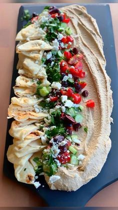 an artisan tortilla is topped with fresh vegetables and feta cheese on a blue platter