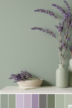 some vases with purple flowers in them on a shelf next to a green wall