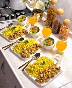 an assortment of food is displayed on a table with utensils and cups in front of it