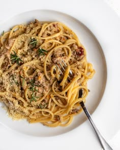 pasta with meat and parmesan cheese on a white plate next to a fork