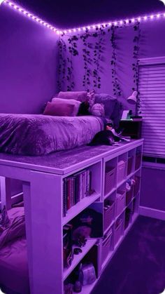 a bedroom with purple walls and lots of bookshelves in the corner, all lit up by string lights