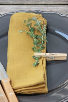 a place setting with napkins, fork and knife on a plate in front of a wooden table