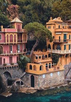 an aerial view of some buildings on the water's edge with trees in the background