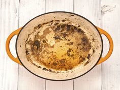 an old dirty pot is sitting on a white wooden table with wood grains and paint