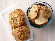 there are cookies and muffins in the plastic container on the white table top