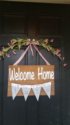 a welcome home sign hanging on the front door with pink and white bunting around it