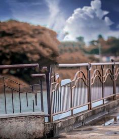 a man walking across a bridge next to the ocean with an umbrella over his head