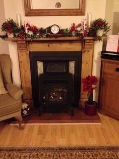 a living room filled with furniture and a fire place covered in christmas wreaths on the mantle