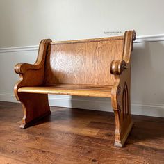 a wooden bench sitting on top of a hard wood floor next to a white wall