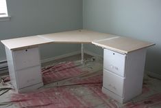 a white desk sitting on top of a hard wood floor next to a window in a room