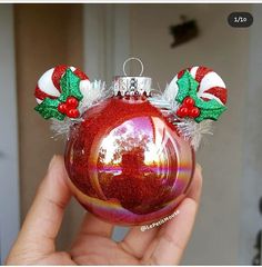 a hand holding a red ornament with green and white decorations