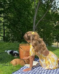 a woman sitting on top of a blue and white checkered blanket next to two dogs