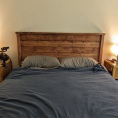 a bed with two lamps on either side and a wooden headboard in the middle