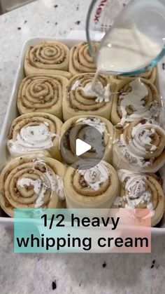 a pan filled with cinnamon rolls covered in icing next to a bottle of milk