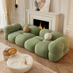 a large green couch sitting on top of a wooden floor next to a fire place