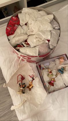 two boxes filled with christmas ornaments sitting on top of a white sheet covered tablecloth