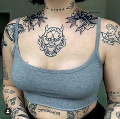 a woman with lots of tattoos on her chest and arms, wearing a gray tank top