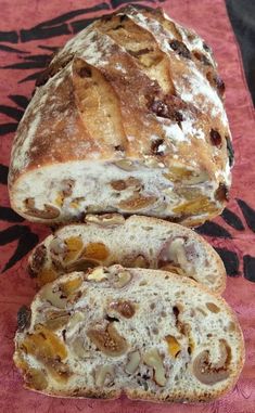 two loaves of bread sitting on top of a red tablecloth with black and white designs