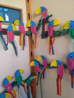 colorful paper birds are hanging on the wall