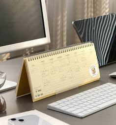 a desk with a calendar, keyboard and mouse on it next to a computer monitor