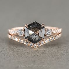 an engagement ring with black and white diamonds on the side, set in 18k rose gold