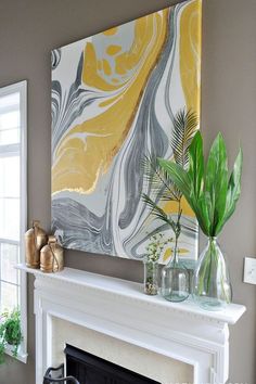 a white fireplace mantel topped with a vase filled with green plants next to a painting