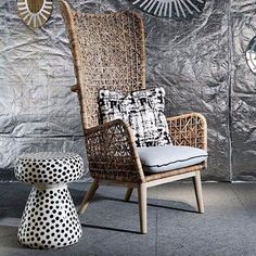 a wicker chair and foot stool in front of a metallic wall with sunbursts on it