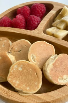 some pancakes and raspberries are in a wooden bowl