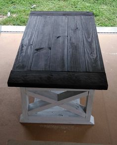 a wooden bench sitting on top of a cement floor next to a grass covered field