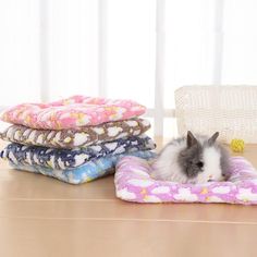 a small hamster is sitting on a pile of blankets next to pillows and a basket