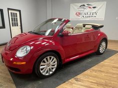 a red convertible car is parked in a showroom with a sign that says quality autos