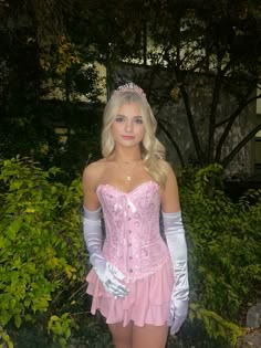 a woman in a pink corset and white gloves posing for the camera with her hands on her hips