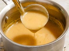 a ladle full of liquid being poured into a pot