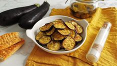 an eggplant and toasted bread dish on a yellow towel next to some other food items