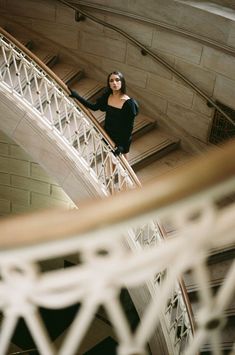 a woman is standing on the top of a staircase in a building with white railings