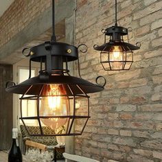 two light fixtures hanging from the ceiling next to a brick wall with bottles on it