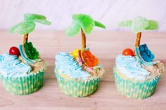 three cupcakes decorated with beach scenes and palm trees