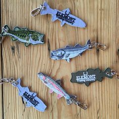 six fish shaped key chains are on a wooden surface, with the words salmon nation printed on them