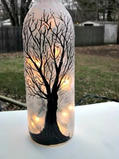 a bottle with lights in the shape of a tree is sitting on a table outside