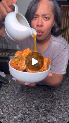 a woman pouring sauce into a bowl filled with food