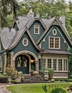 a blue house with lots of windows in the front yard and steps leading up to it