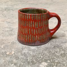 a red and brown cup sitting on top of a cement floor