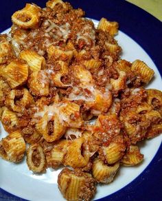 a white plate topped with pasta covered in sauce and cheese on top of meaty noodles