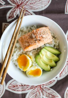 salmon, eggs and avocado on rice in a bowl with chopsticks