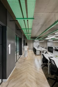 an office with wooden floors and white desks on each side, along with green lighting