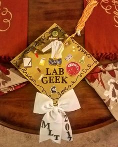 a graduation cap that is sitting on top of a wooden table with red and white pillows