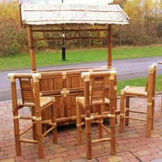 a wooden table with four chairs and an umbrella over it on a brick patio area